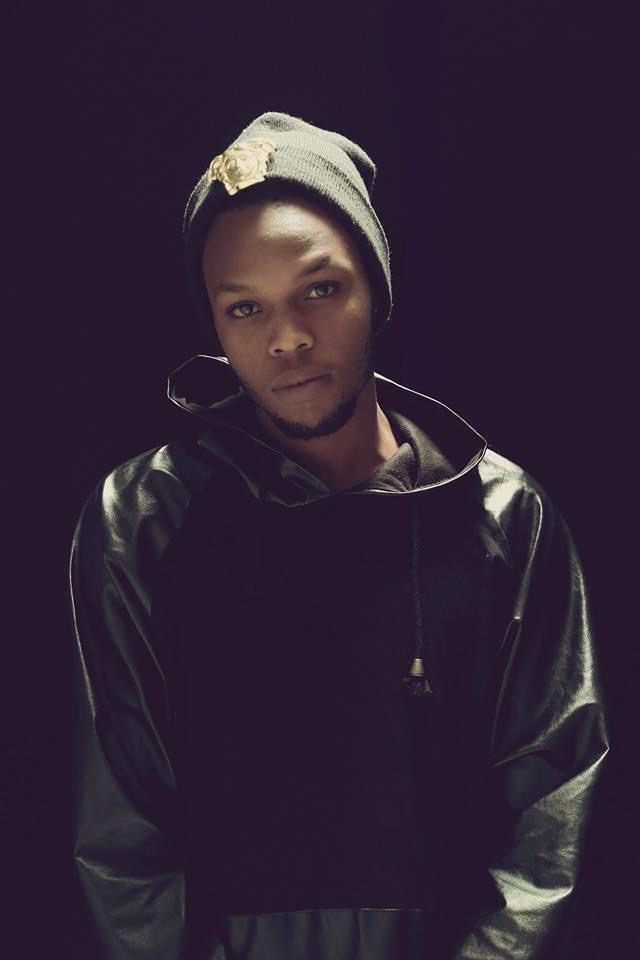 Delboy in a black hoodie and beanie against a dark background