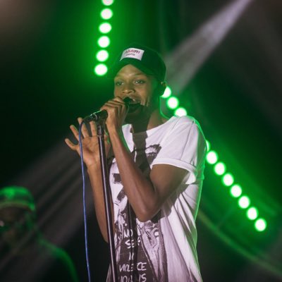 Delboy holding a microphone on stage under green lights